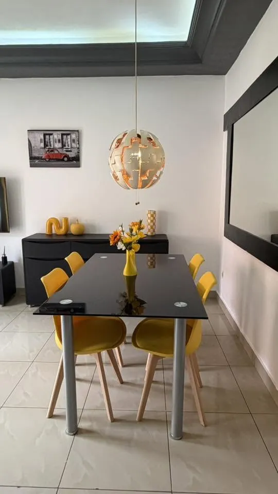 Salle à manger avec table en verre et chaises jaunes