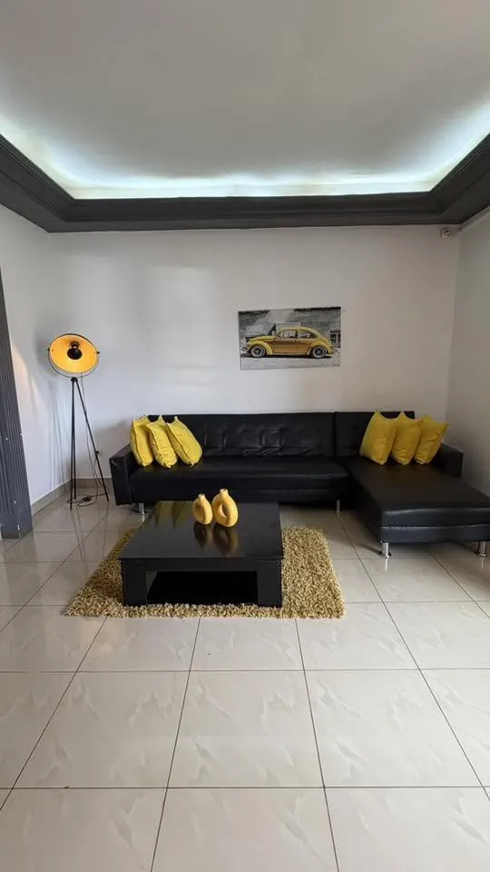Salon avec canapé d'angle noir et coussins jaunes